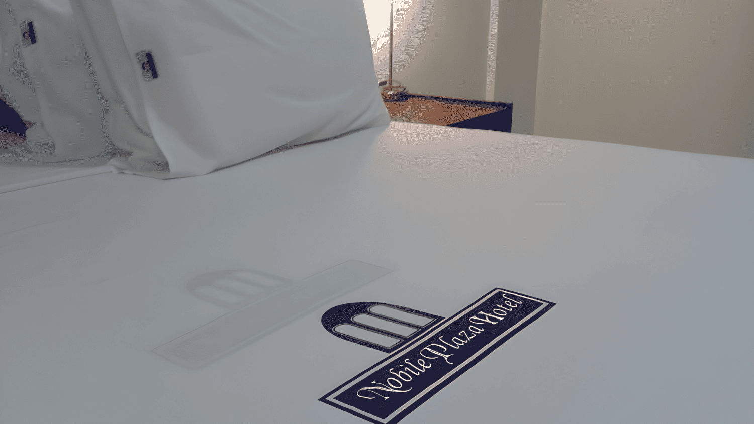 Uma cama de hotel com lençóis e travesseiros brancos e um logotipo na cama