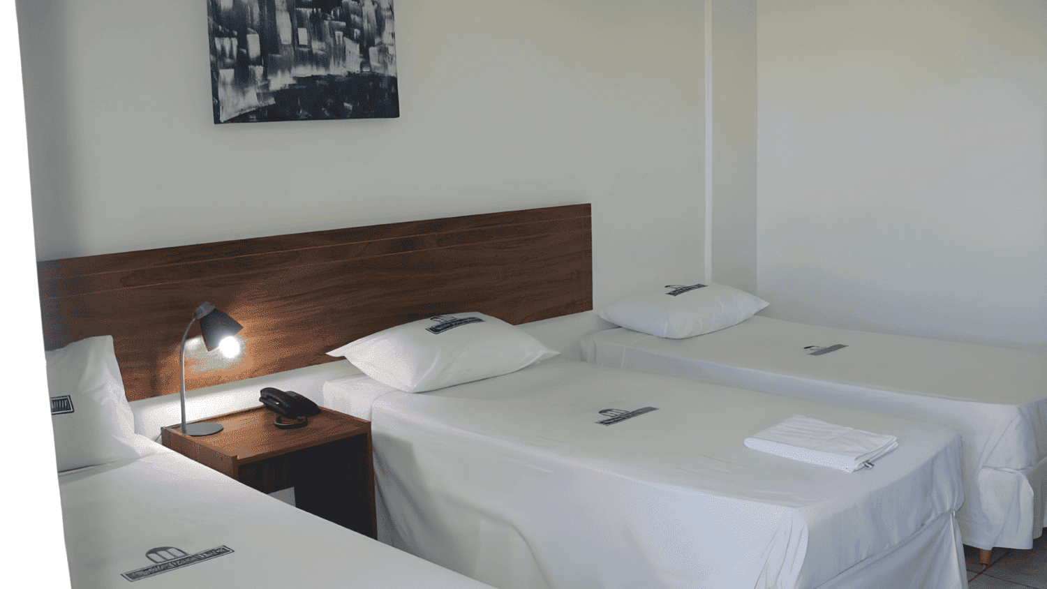 Um quarto de hotel com três camas e uma foto na parede