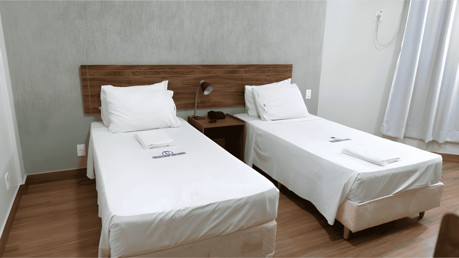 Um quarto de hotel com duas camas e uma mesa de cabeceira.