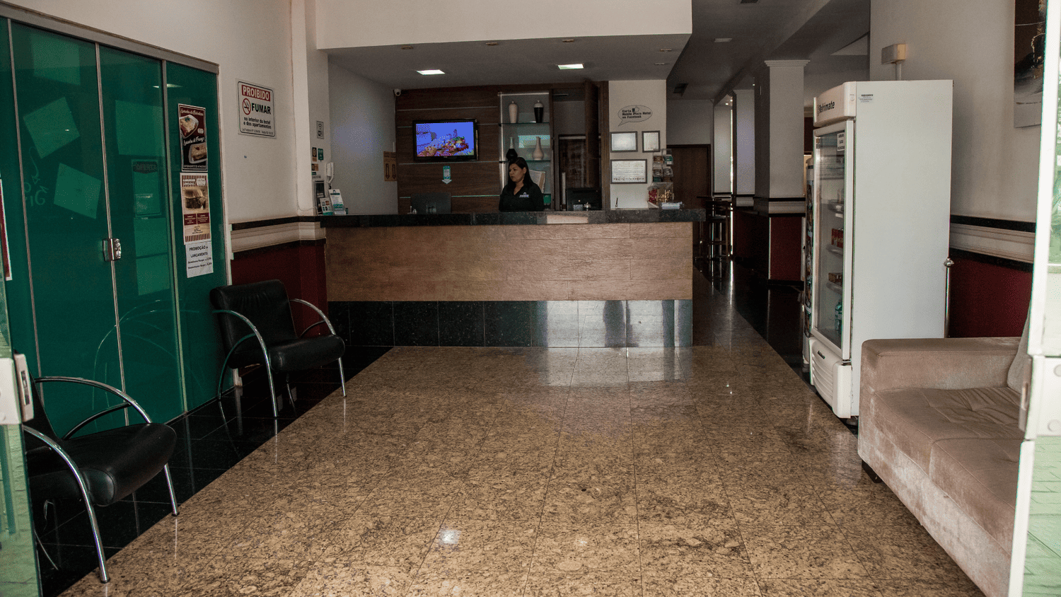 Um lobby de hotel com um sofá, cadeiras e um balcão.