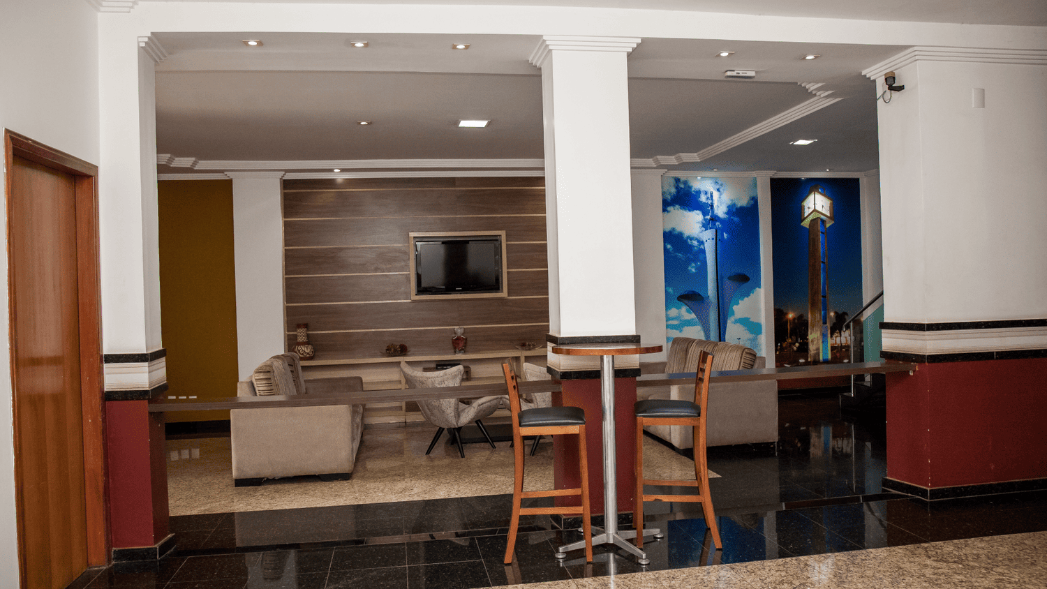 Um saguão de hotel com uma mesa, cadeiras e uma televisão.