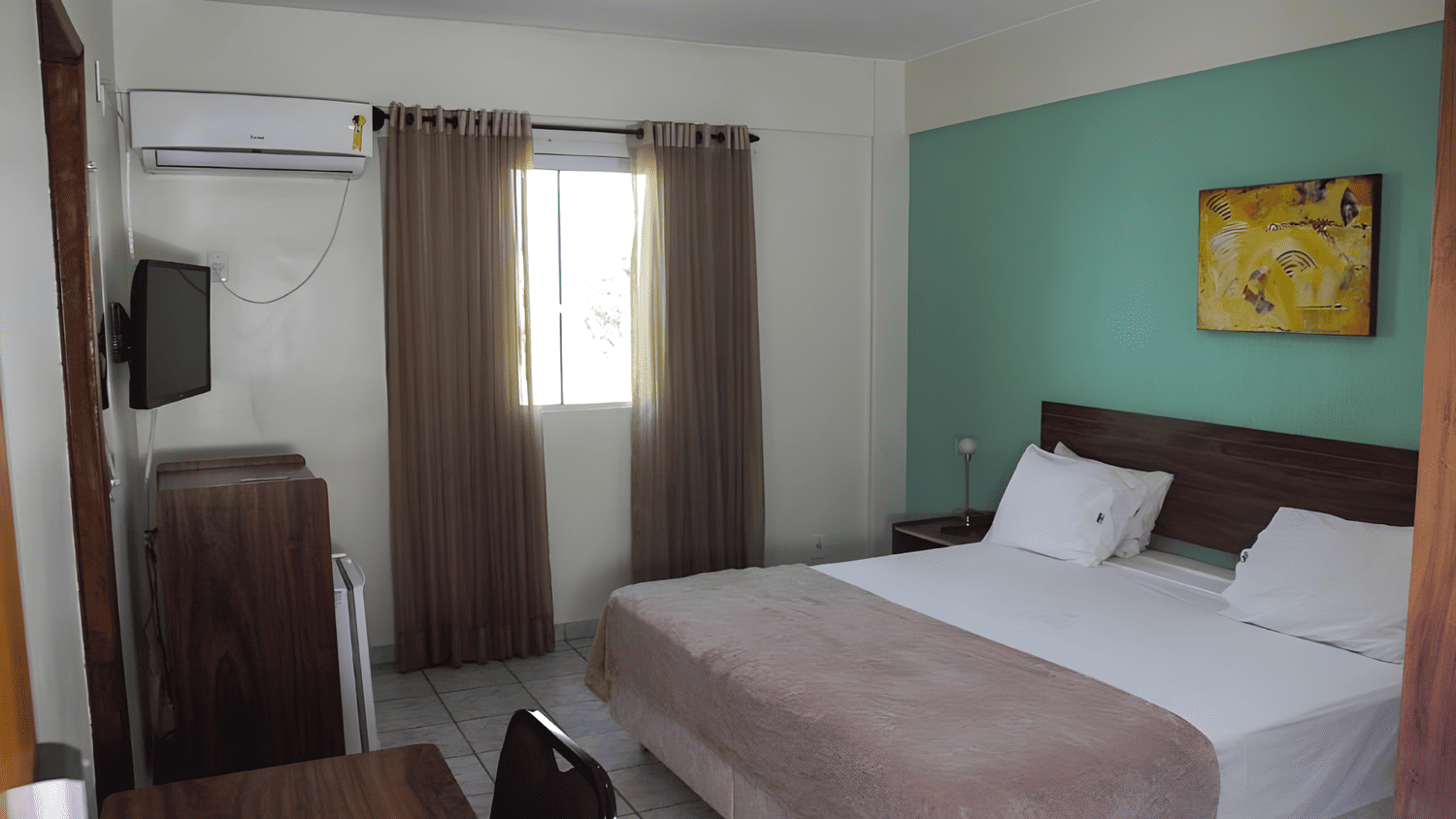 Um quarto de hotel com uma cama king size e uma TV de tela plana.