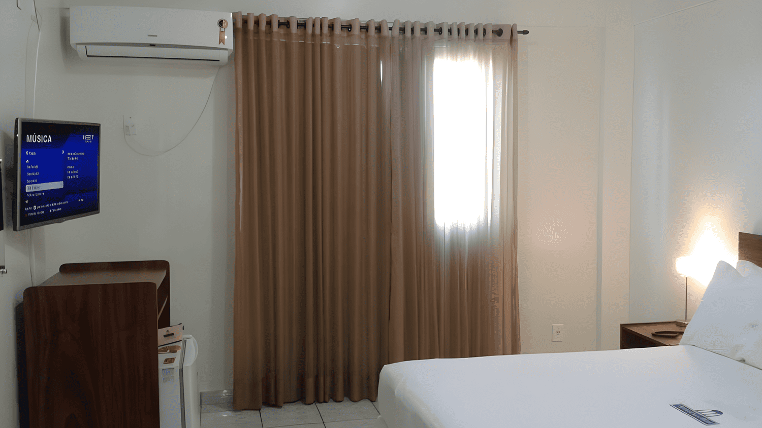 Um quarto de hotel com cama, televisão e ar condicionado.