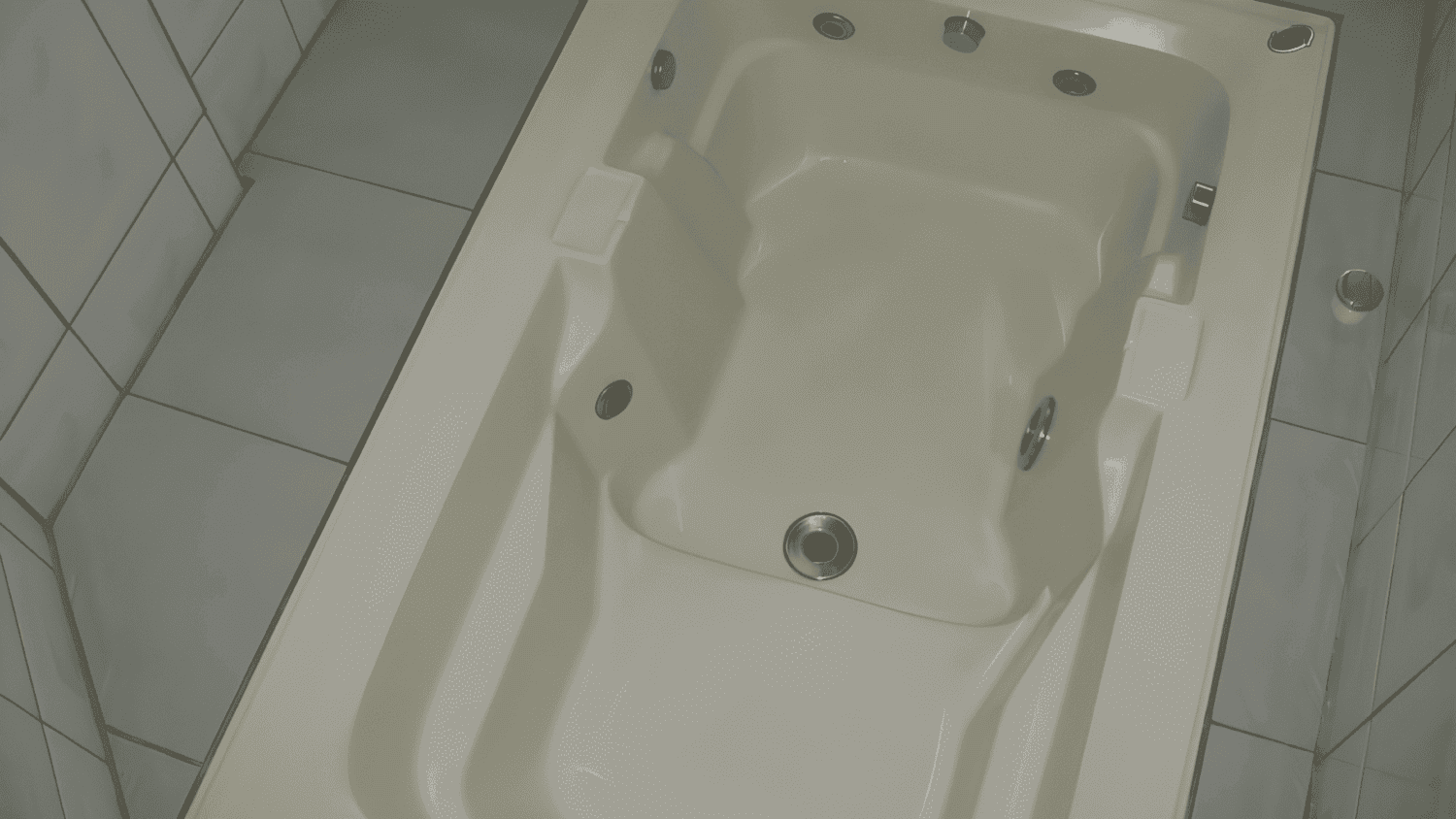 Uma banheira branca está sobre um piso de ladrilho em um banheiro.