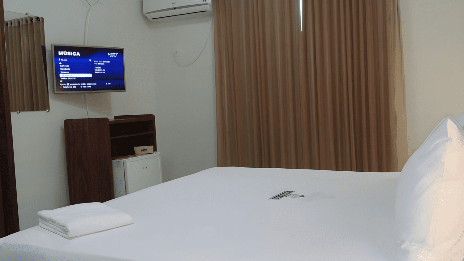 Um quarto de hotel com cama, televisão e ar condicionado.