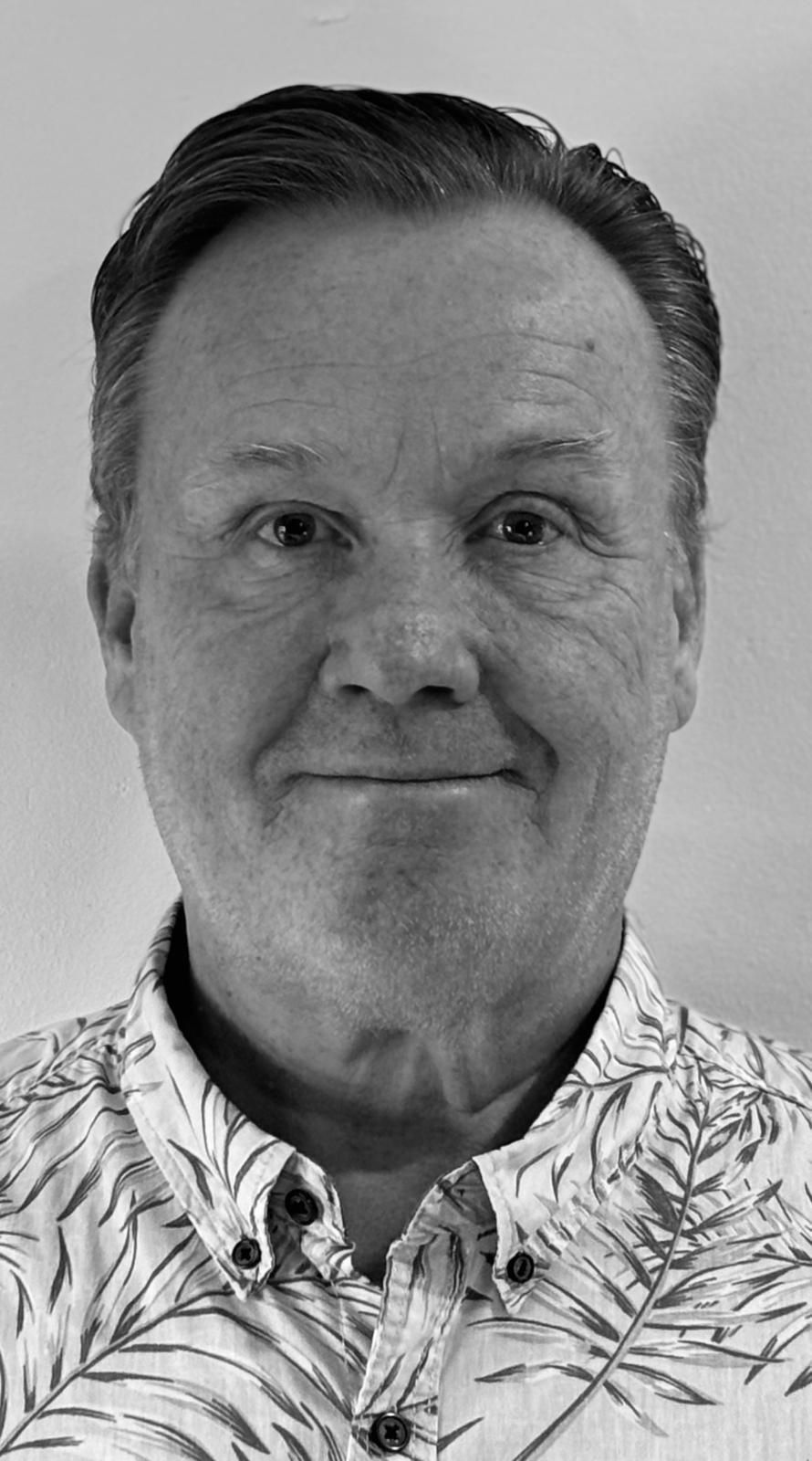 A black and white photo of a man wearing a hawaiian shirt.