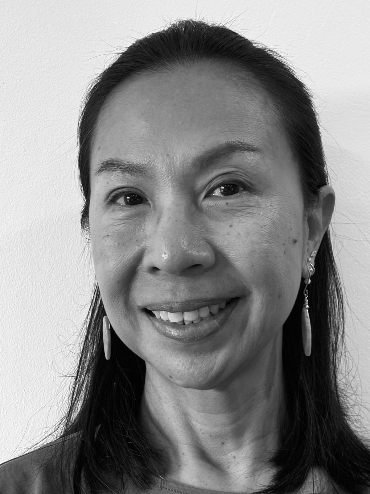 A black and white photo of a woman smiling and wearing earrings.