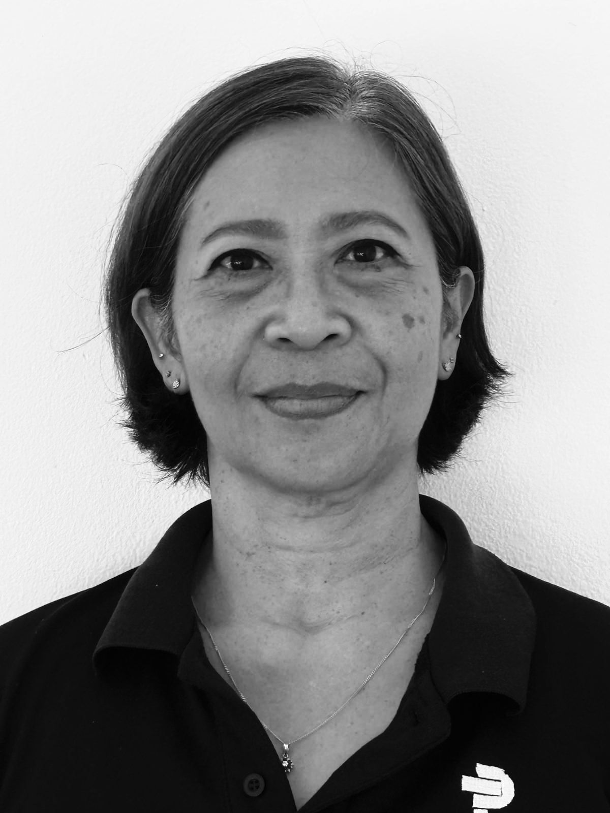 A woman in a black shirt is smiling in a black and white photo.