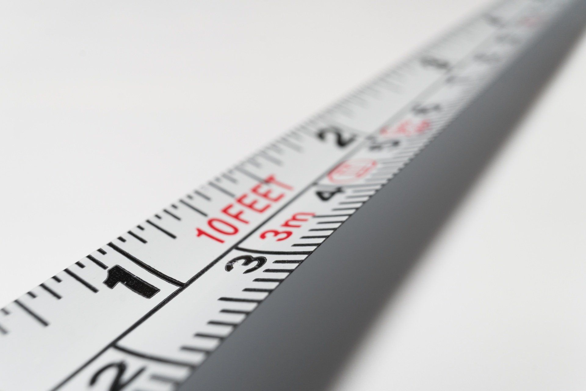 Measuring tape angled on white background, showing feet and meter markings.
