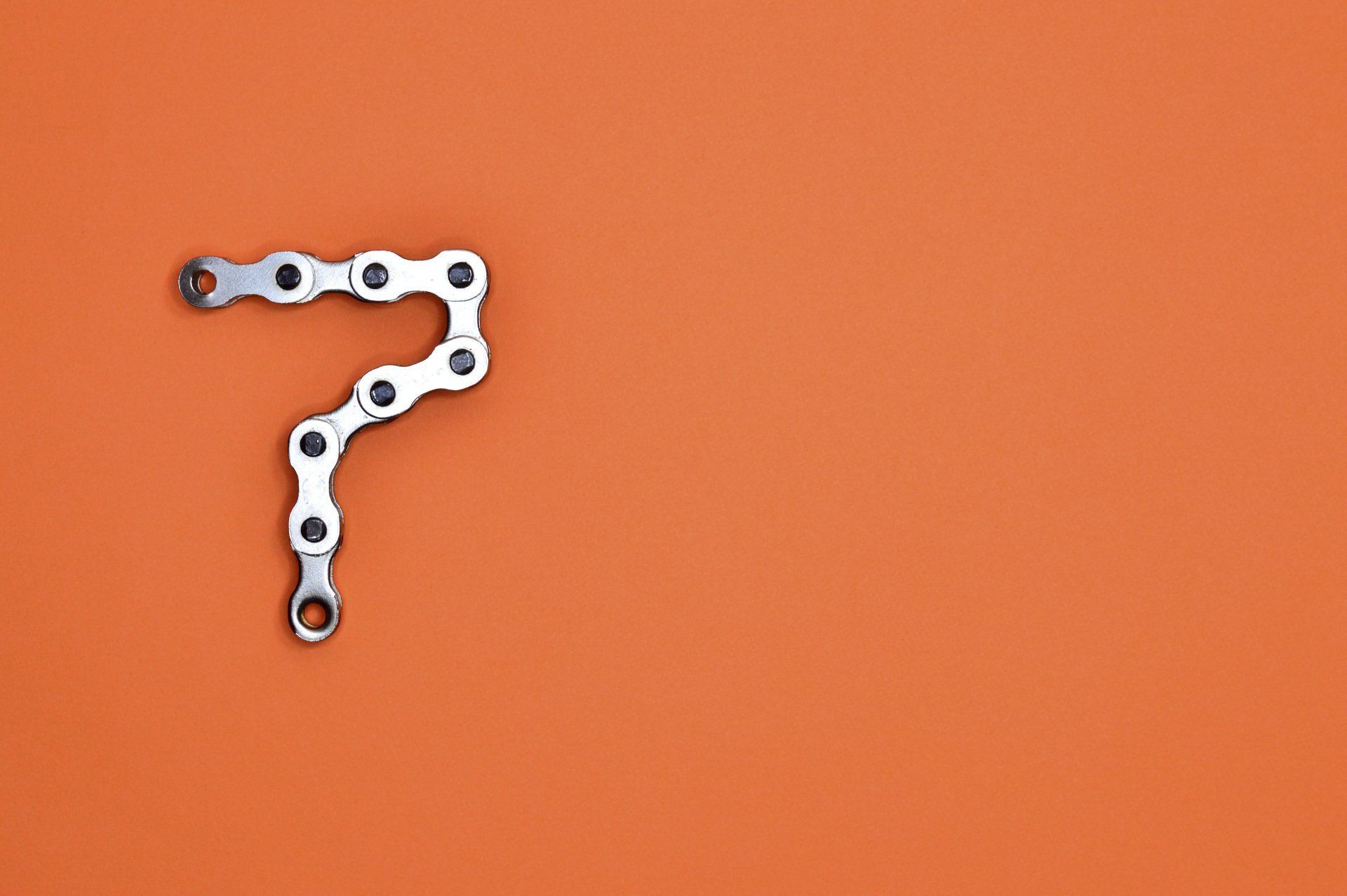 Number 7 made of bicycle chain, on orange background.