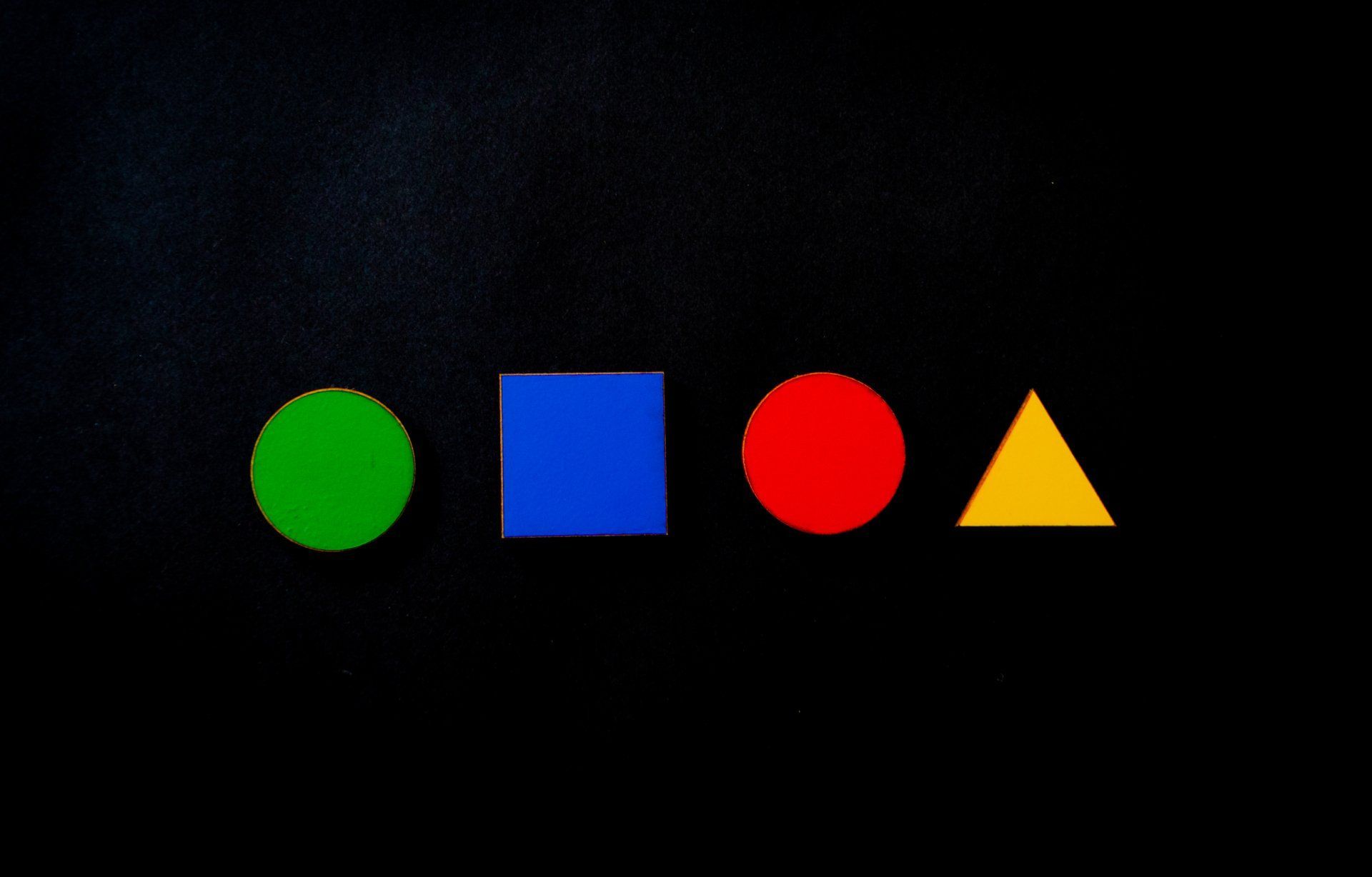 Green circle, blue square, red circle, and yellow triangle on a black background.