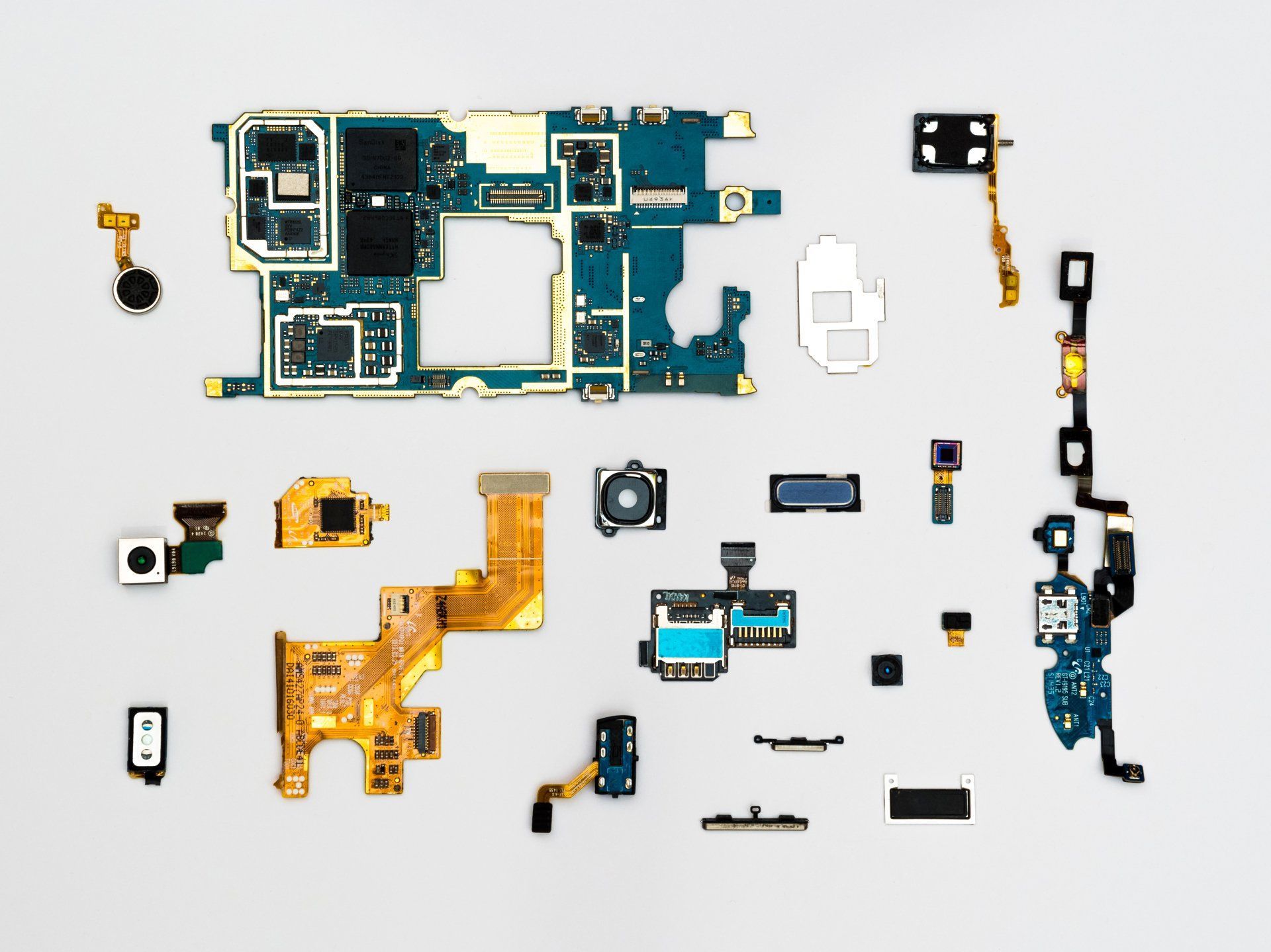 Disassembled smartphone components laid out on a white surface, showcasing circuit boards and camera modules.