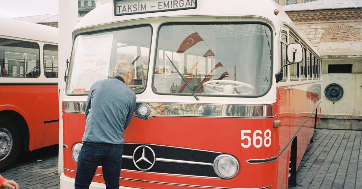 Man examines a vintage red and white bus with 
