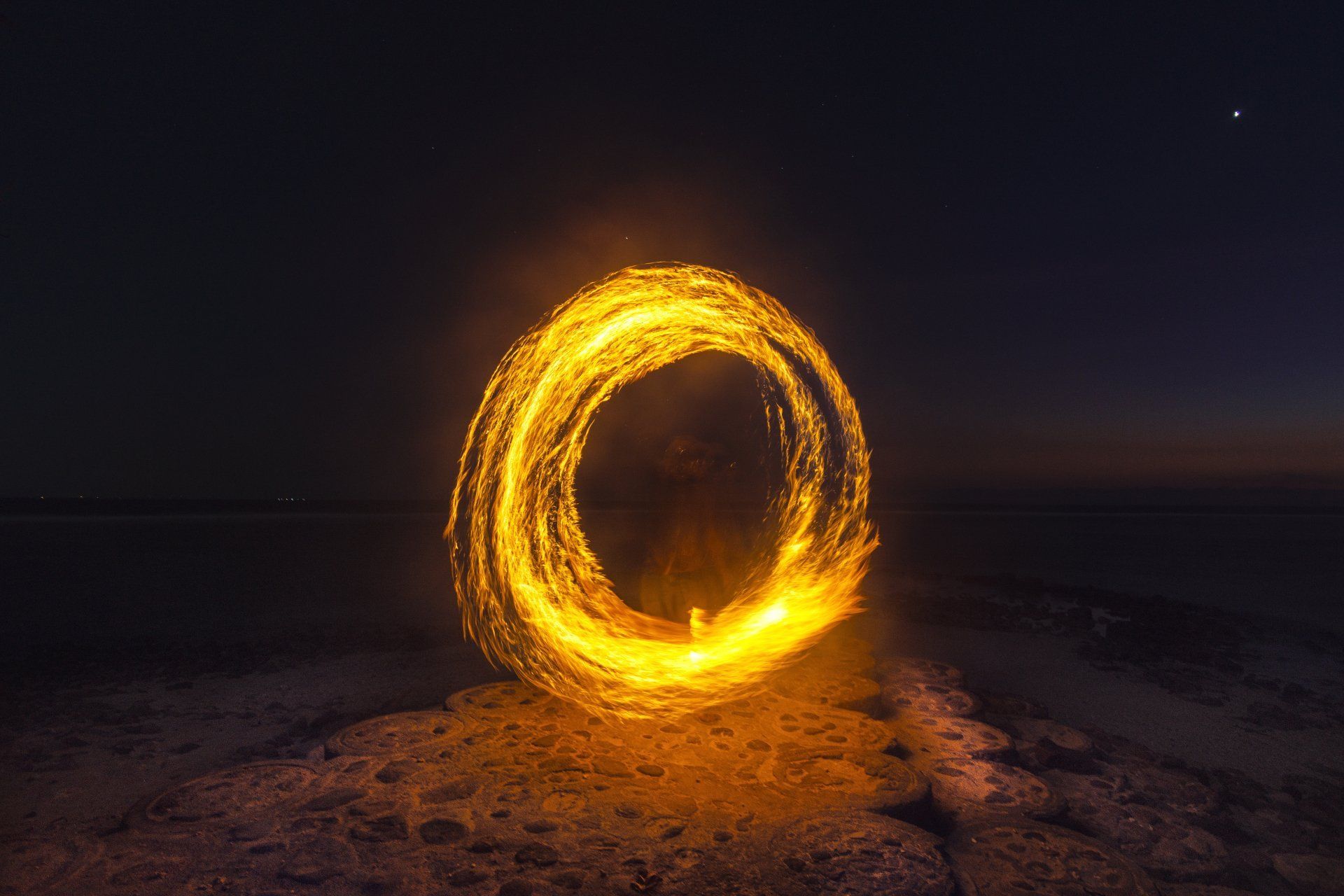 Glowing fire circle against a dark night sky, possibly a long exposure shot.