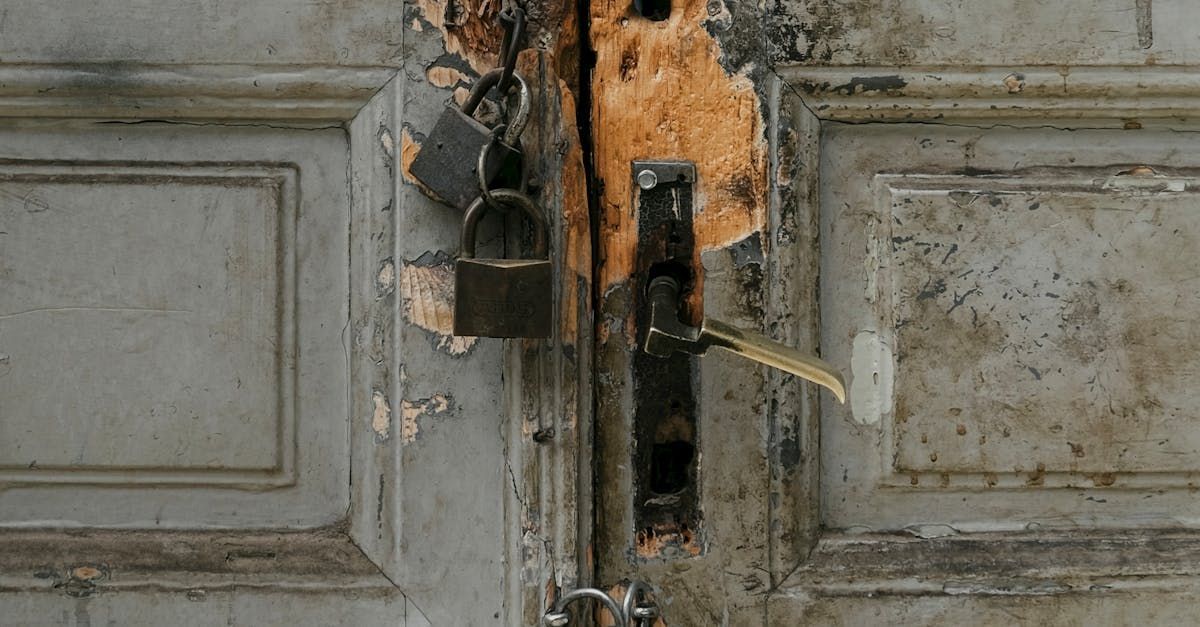 Old, weathered, light blue door with peeling paint, secured by a padlock and rusty hardware.