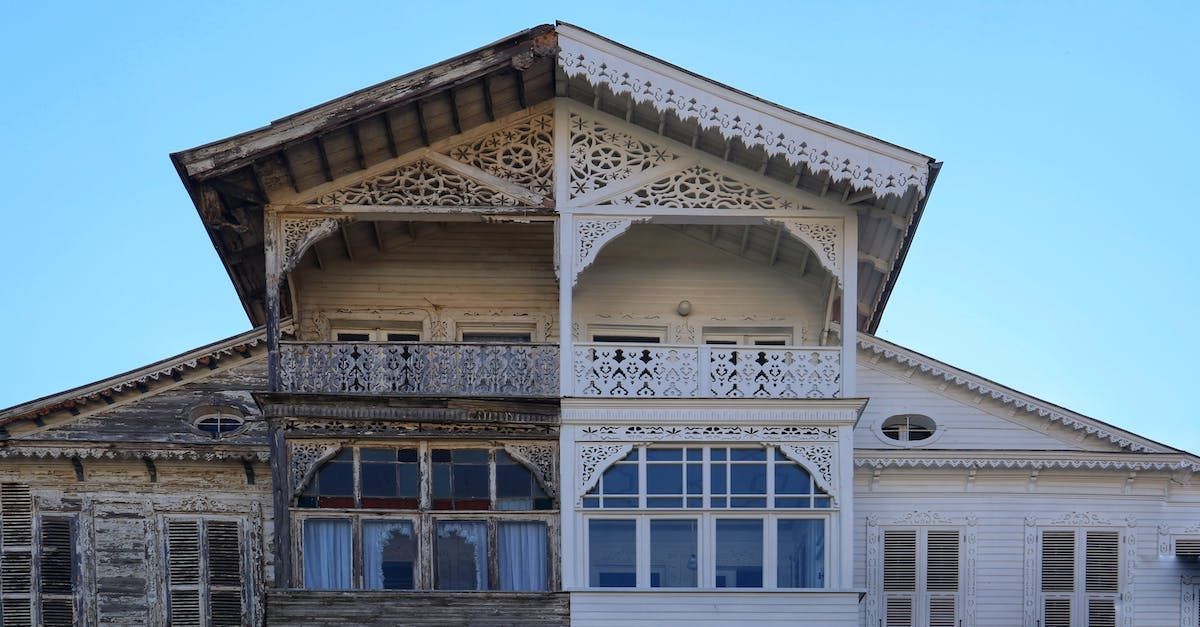 Half-cleaned white wooden house with intricate carvings; shows before/after effects of cleaning.