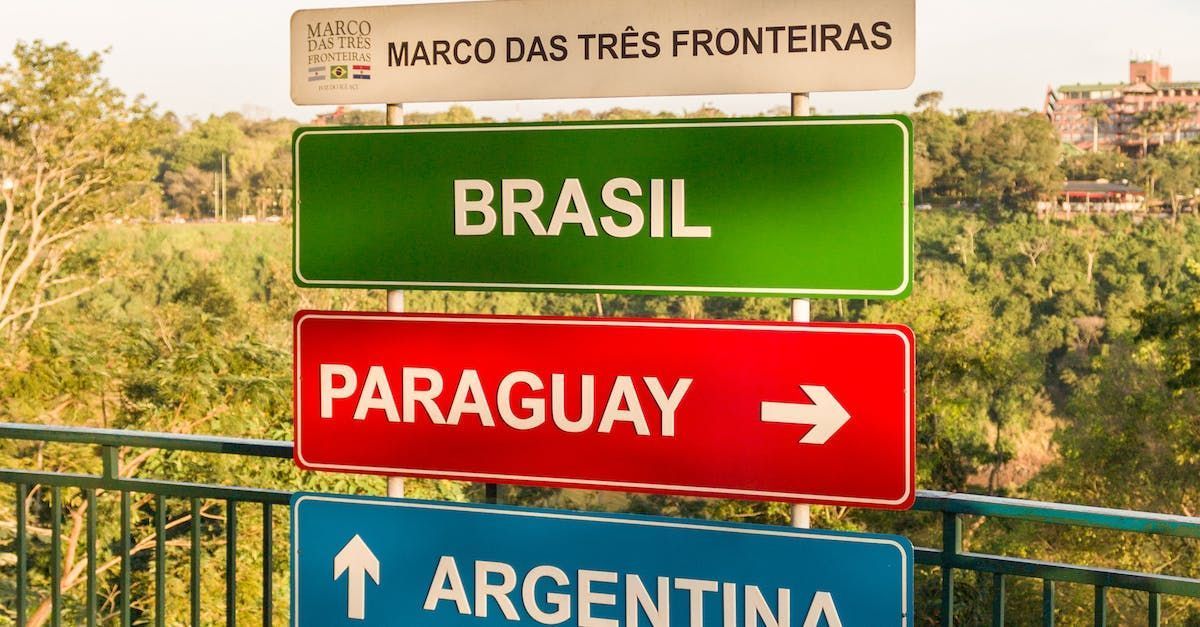 Signposts indicating borders of Brazil (green), Paraguay (red), and Argentina (blue) at the Three Borders Landmark.