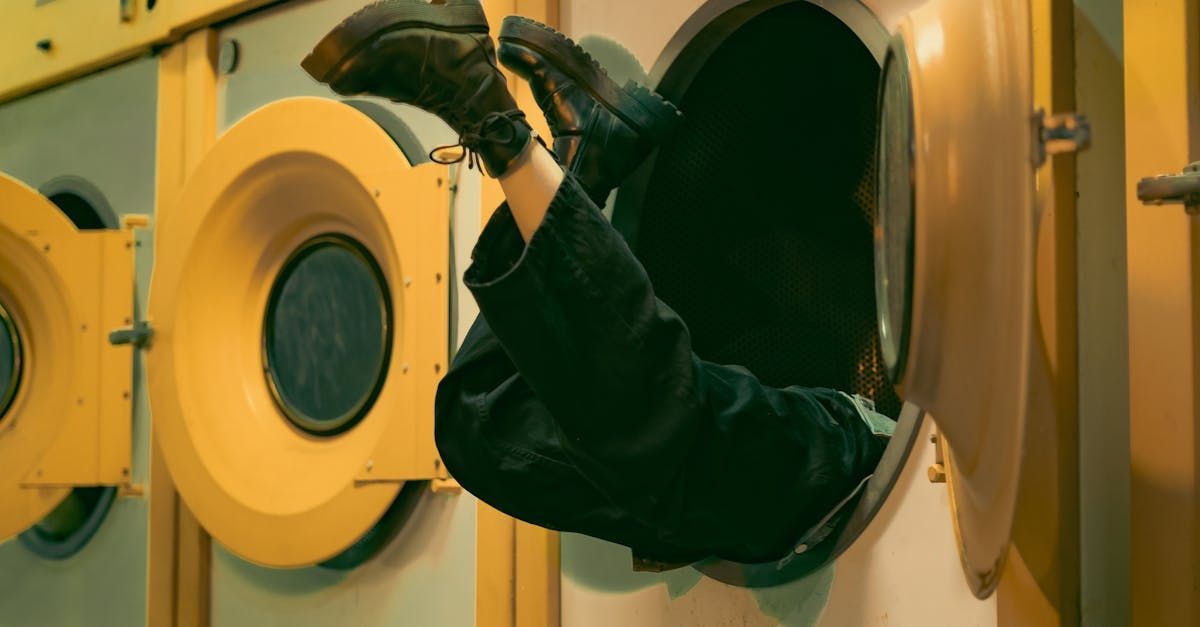 Person stuck headfirst in a yellow washing machine, legs and feet visible.