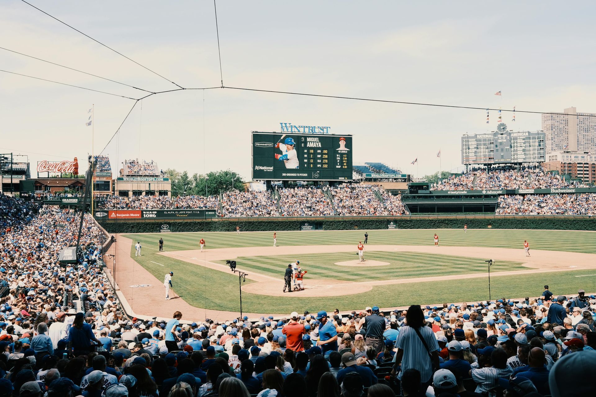 Baseball game at Wrigley Field with a packed crowd and scoreboard.