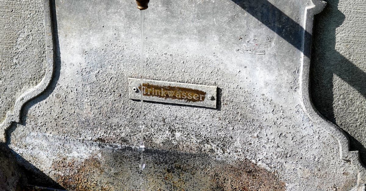 Close-up of a weathered, textured concrete surface with a small rectangular plaque containing engraved text.