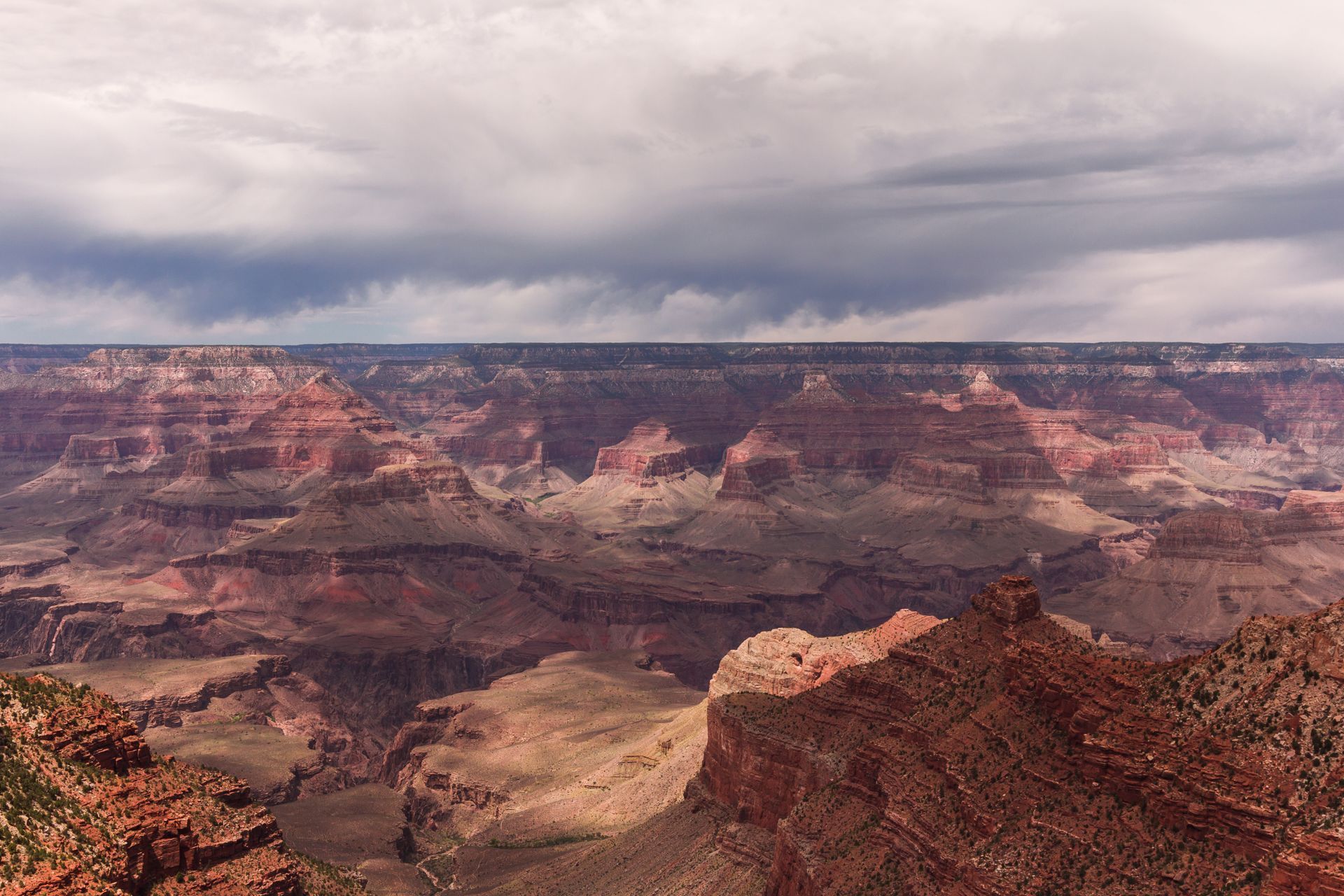 Grand Canyon vista with red rock formations and cloudy sky.
