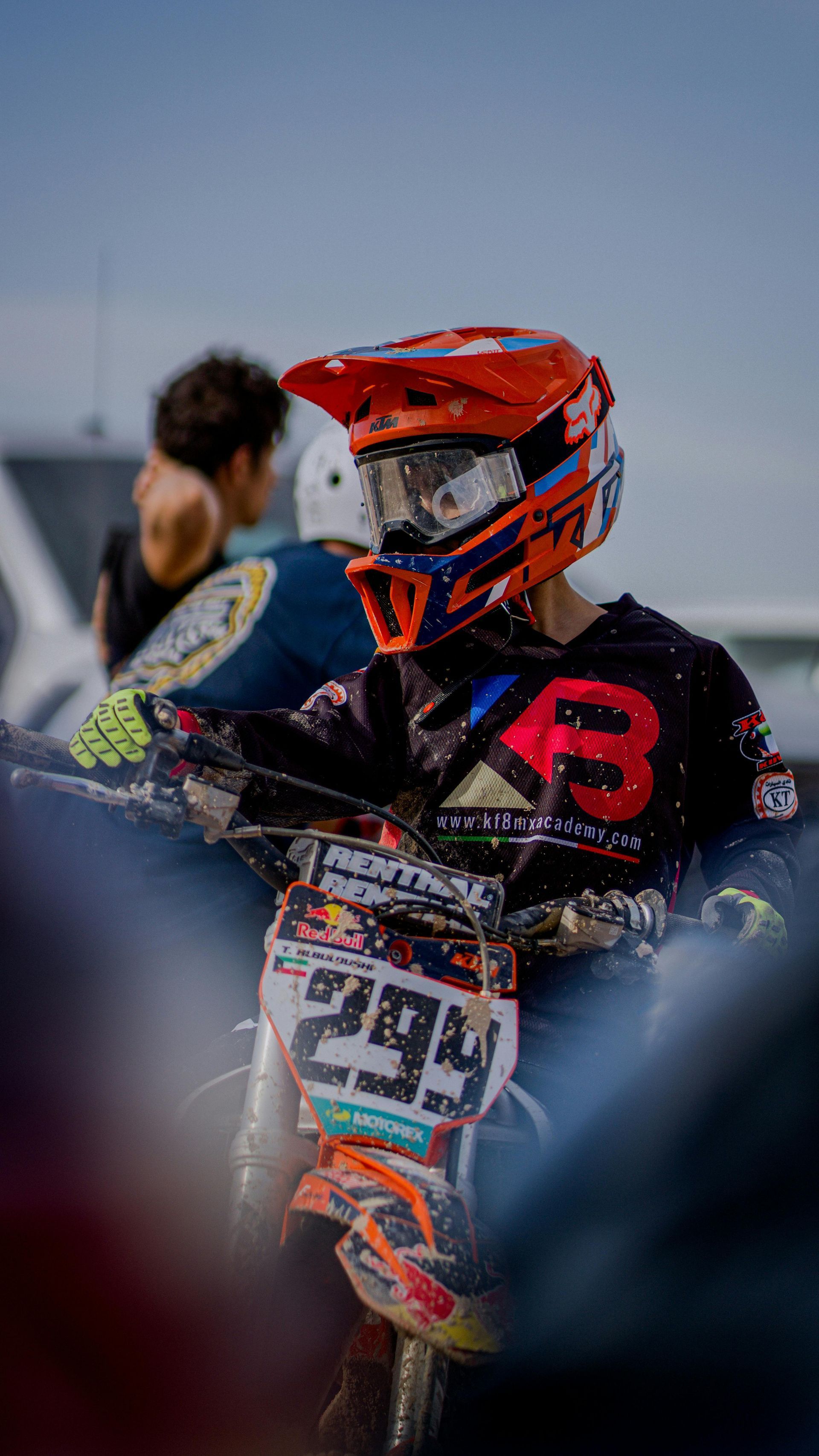 Motocross rider in orange helmet on bike, number 294, near spectators.
