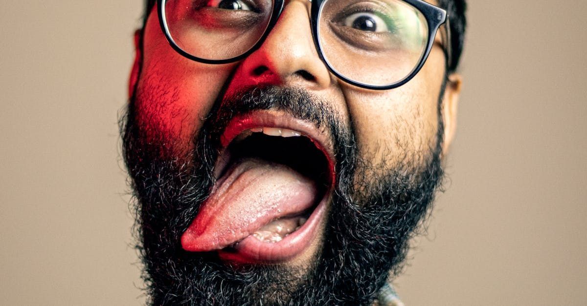 Man with glasses, mouth wide open, tongue extended.