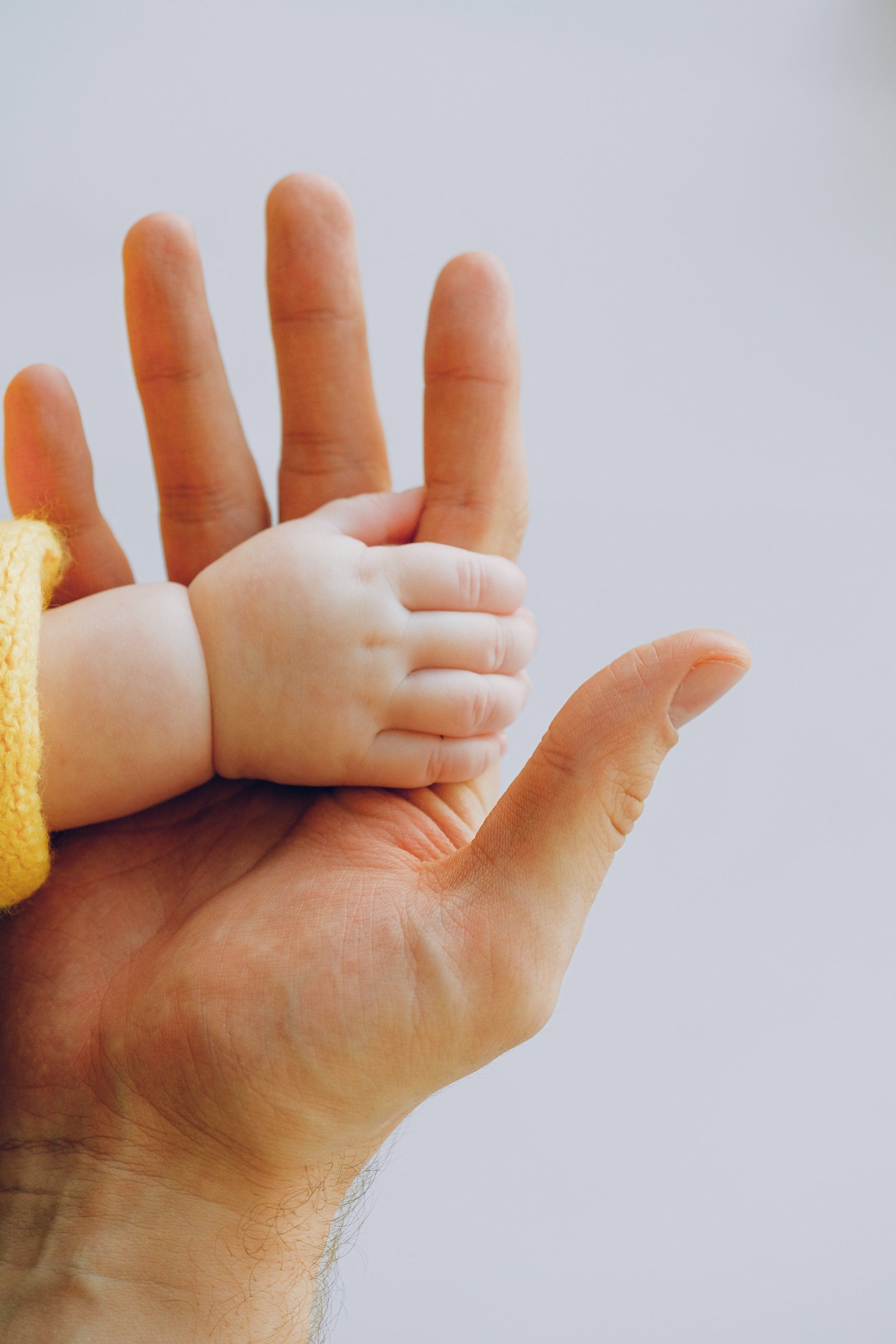 A baby's tiny hand holding an adult's larger hand, symbolizing connection and care.