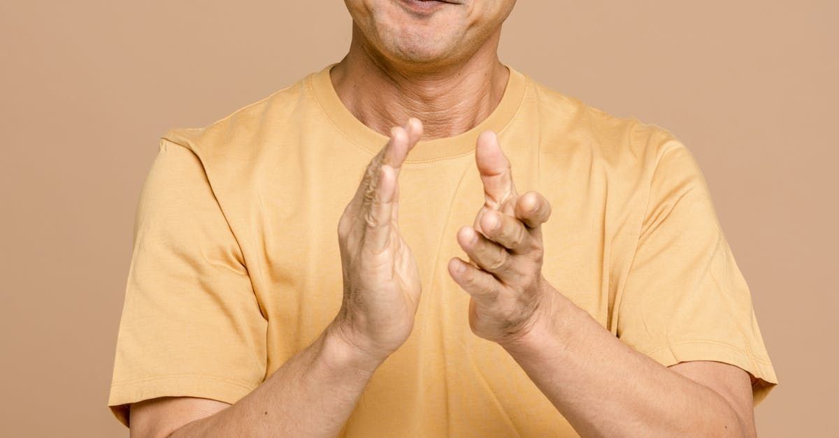 Person in a yellow shirt clapping hands. Beige background.