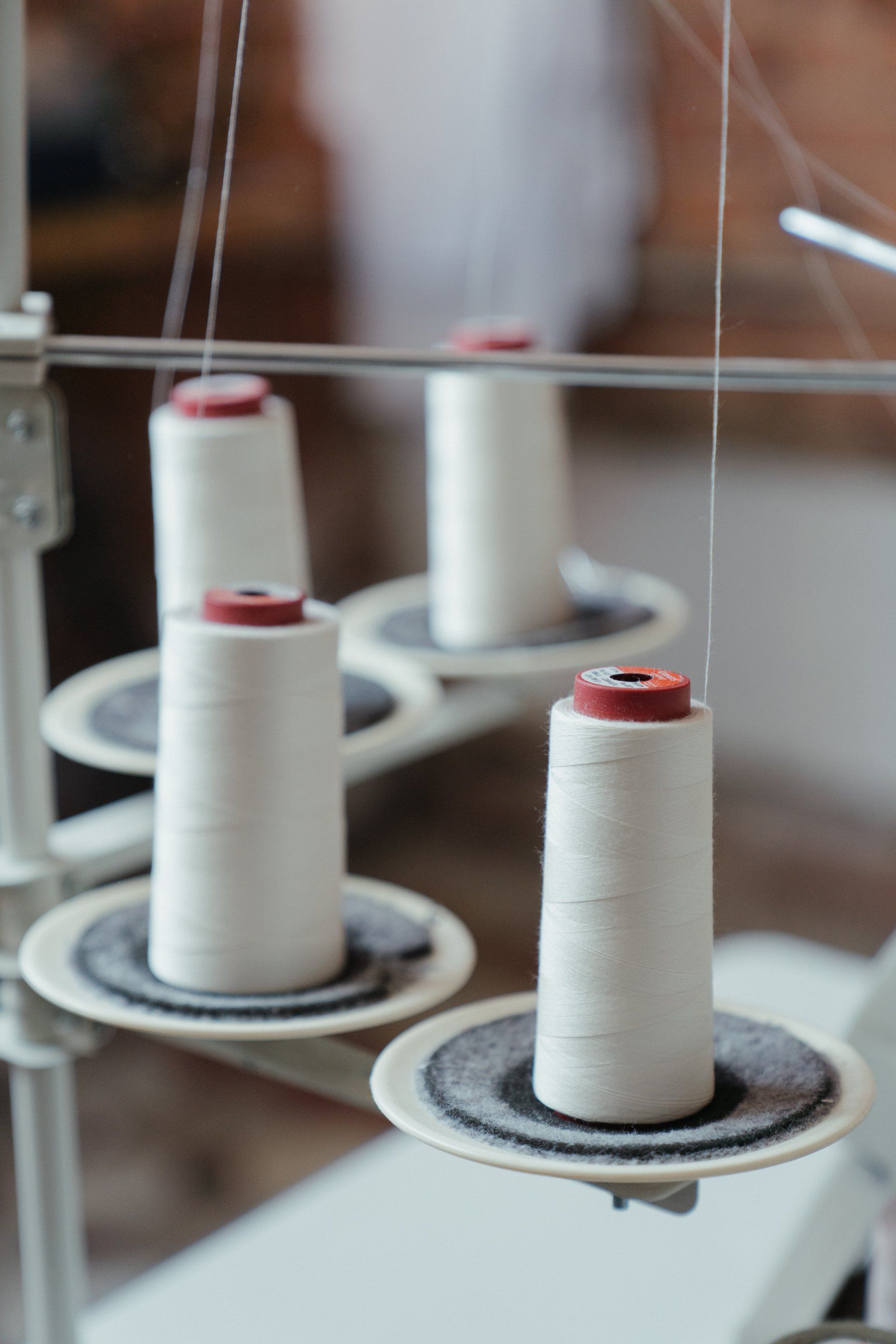 White spools of thread on a machine, ready for sewing in a workshop.
