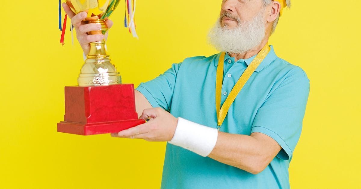 Man holding a trophy with yellow and red accents against a yellow backdrop.