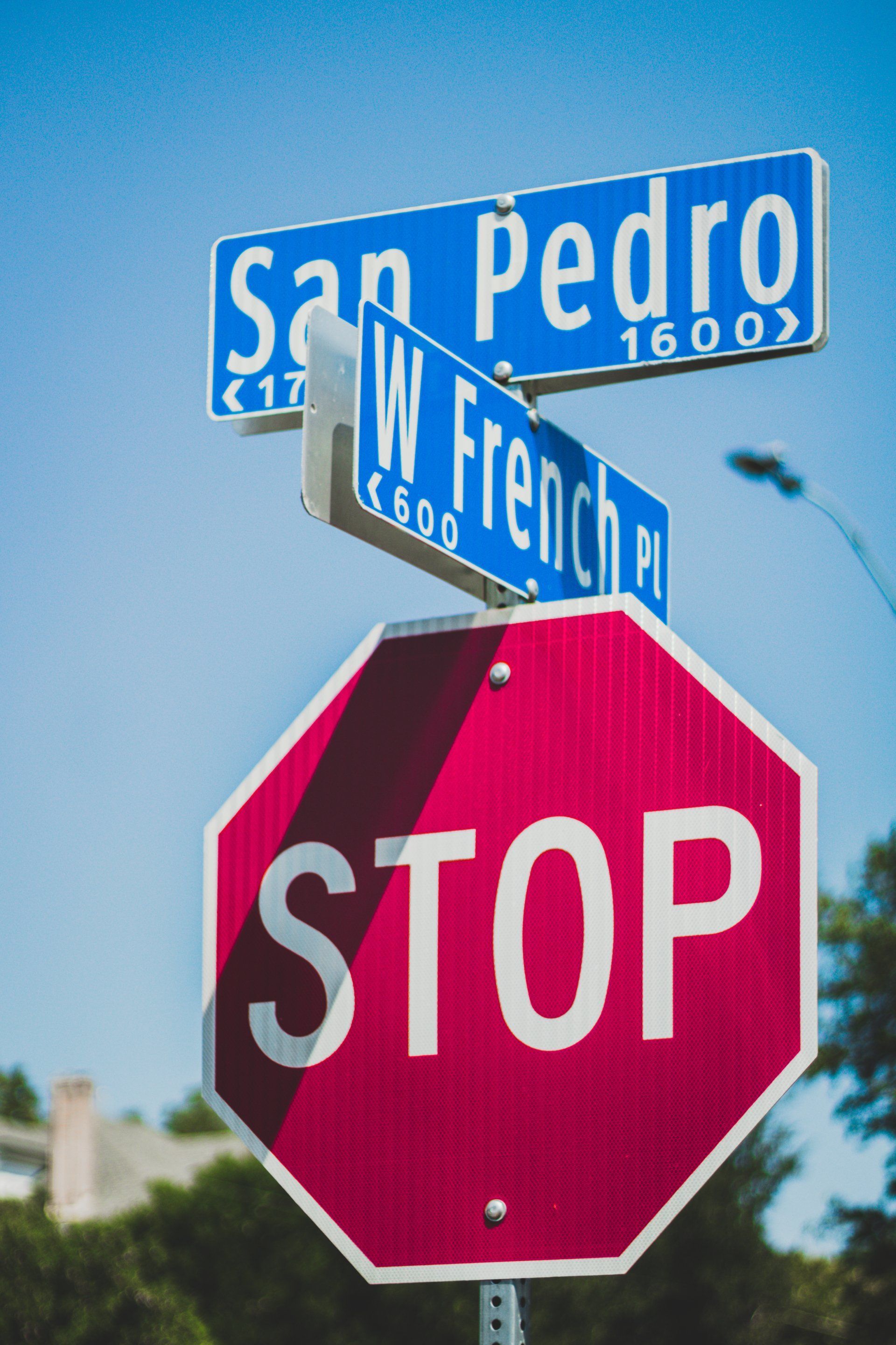 Street signs for San Pedro and W French Pl; Stop sign in foreground.