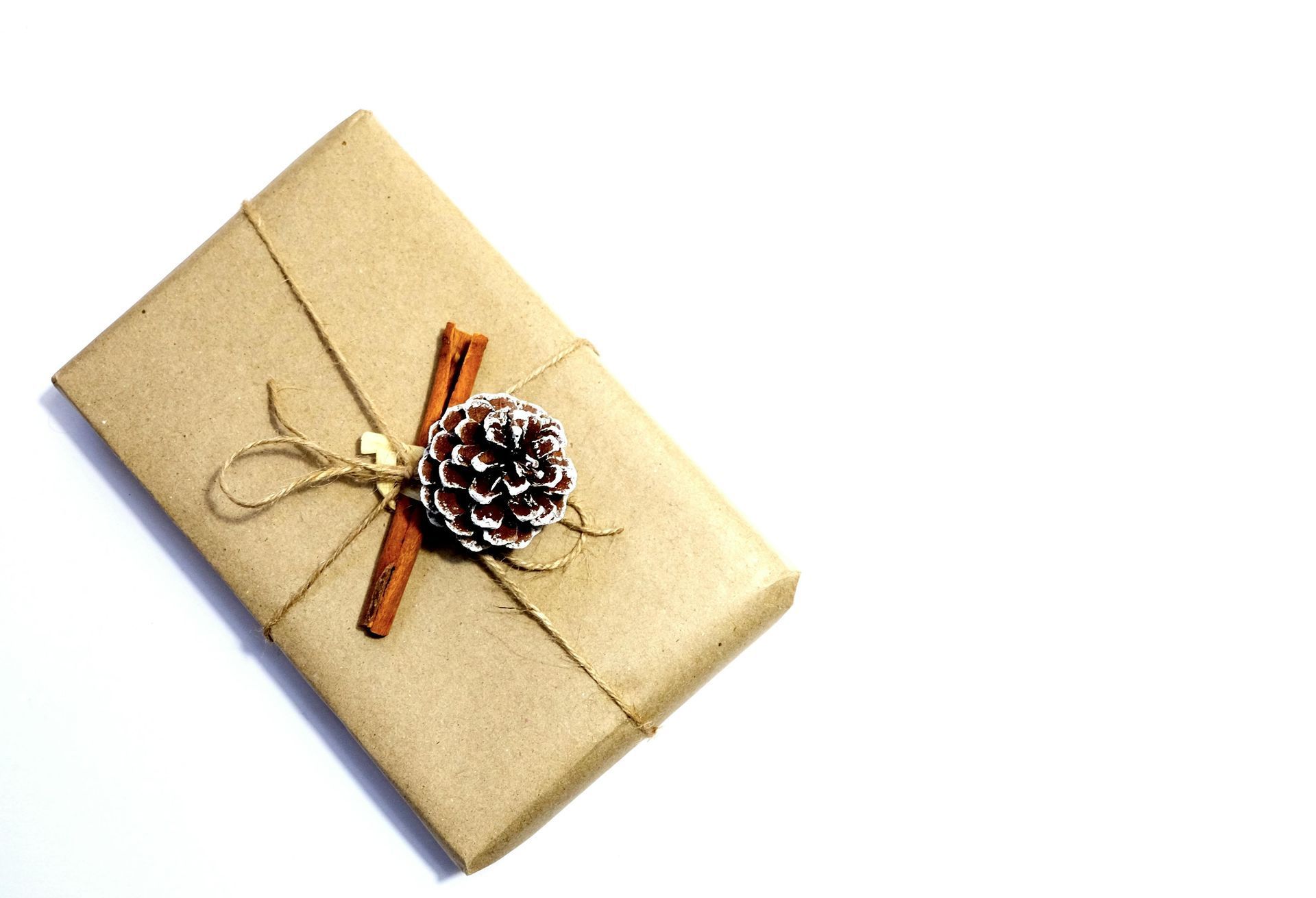 Gift wrapped in brown paper, tied with twine and decorated with a cinnamon stick and pinecone.