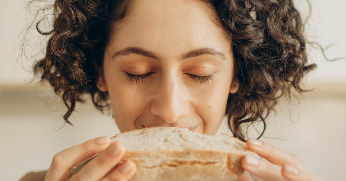 Woman smelling a slice of bread with eyes closed.