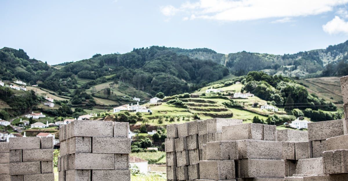 Stone blocks in foreground frame view of lush green hillside dotted with white buildings.