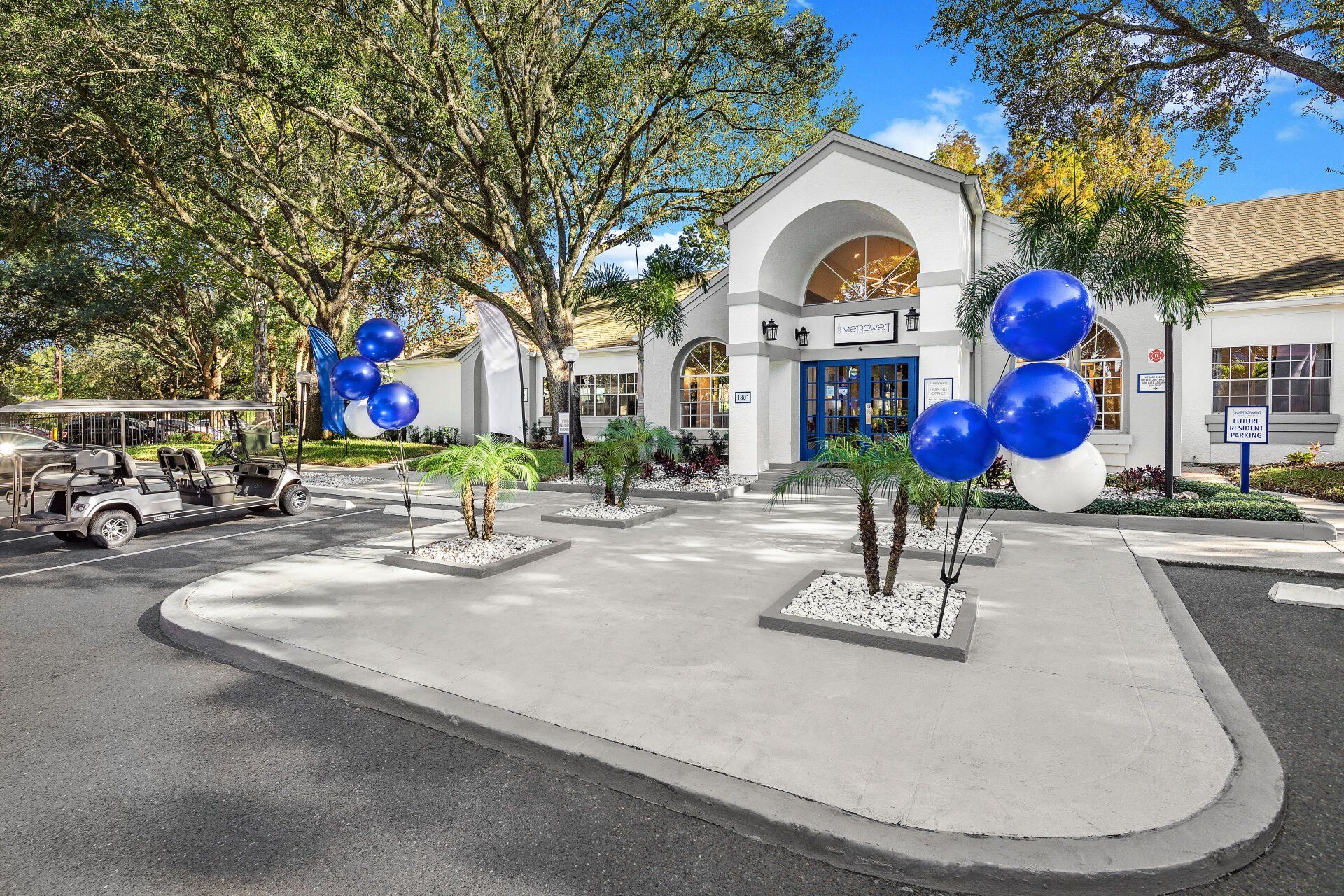 A white building with blue and white balloons in front of it.