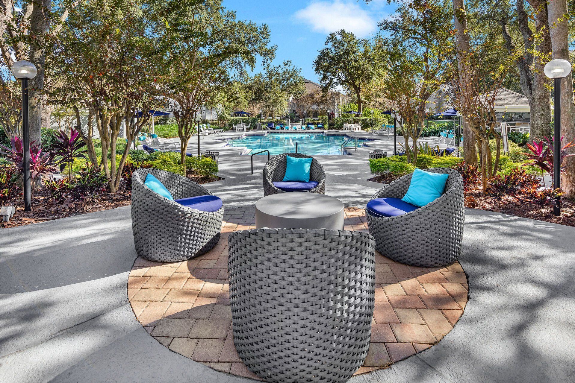 A patio area with wicker furniture and a pool in the background