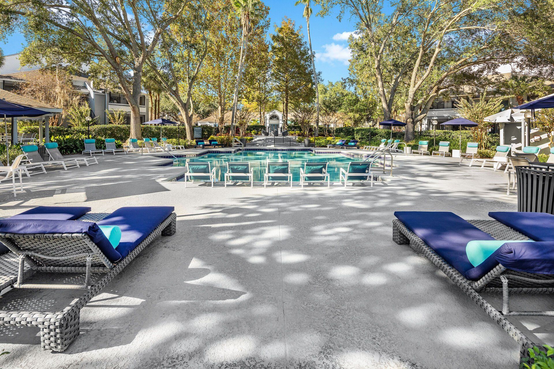 There are a lot of chairs and umbrellas around the pool.