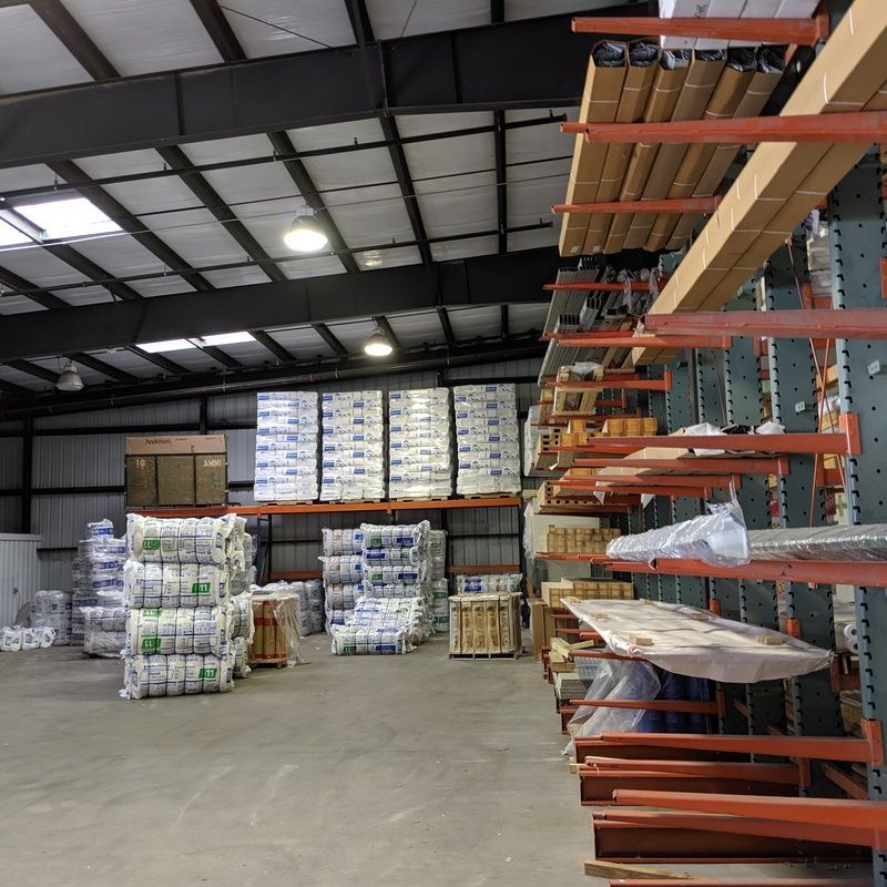 Warehouse interior with shelves and pallets of building supplies.