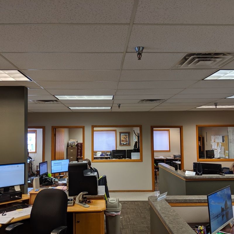 Office cubicles with computers and desks, and doors in a well-lit workspace.