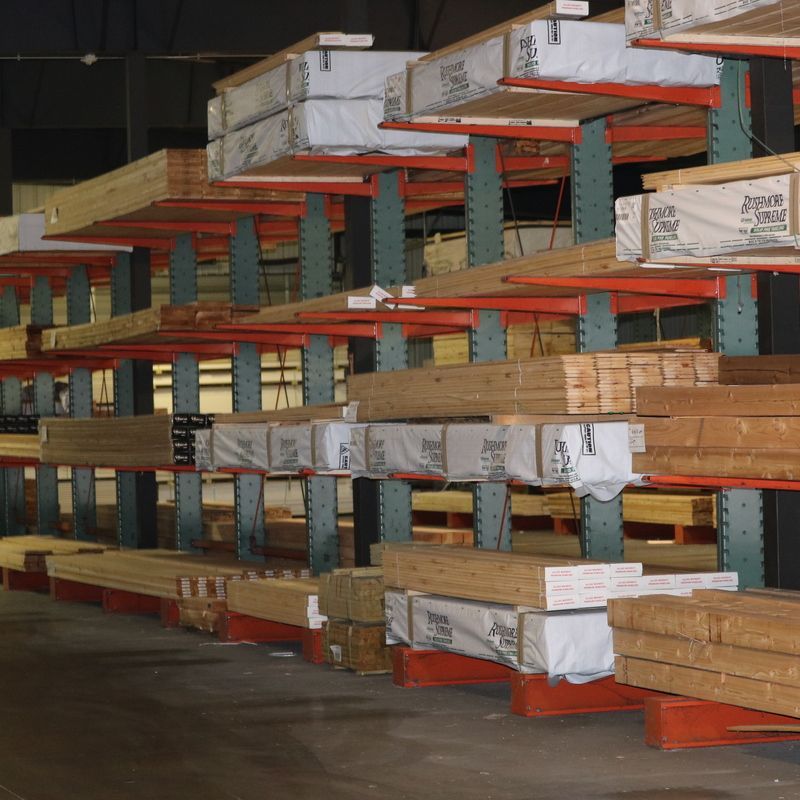 Lumber storage racks in a warehouse, filled with stacks of wood planks and beams.