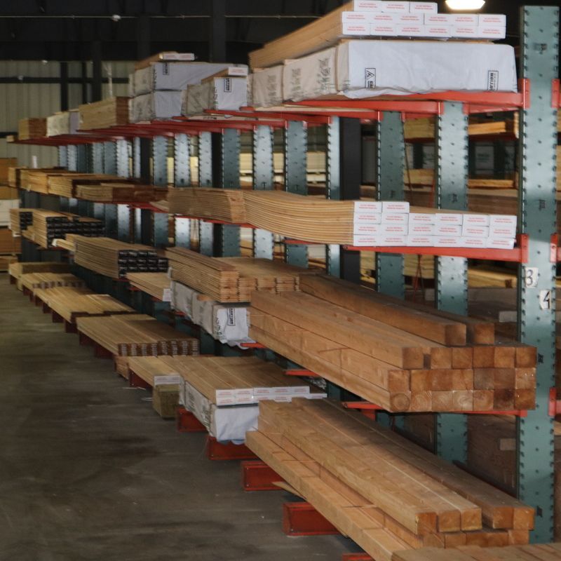 Lumber stacked on industrial shelving in a warehouse; various wood types and sizes.