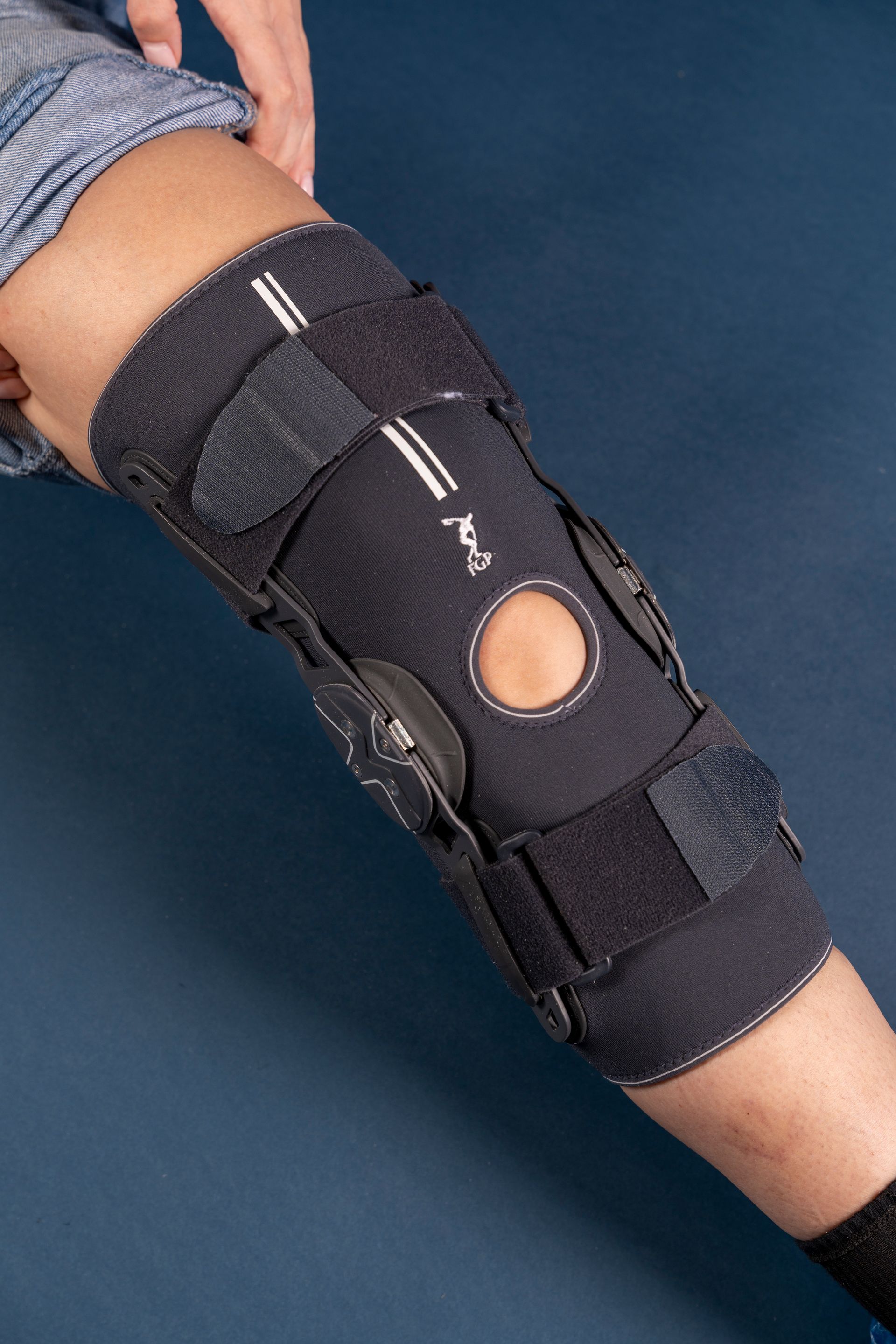 Gamba di una persona con un tutore nero per il ginocchio, cinghie allacciate.