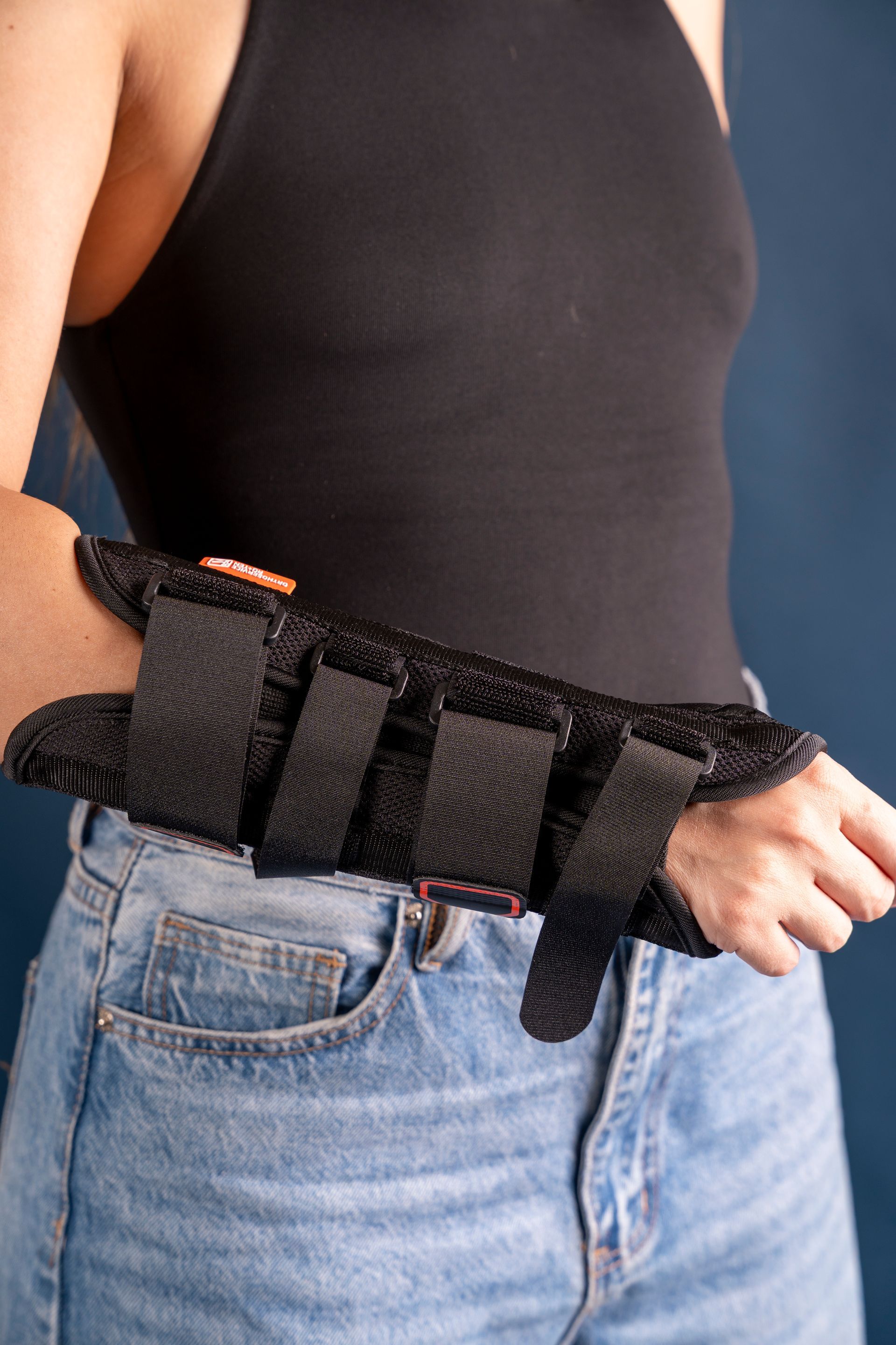 Persona che indossa un tutore nero per il polso sopra una maglietta nera e jeans blu.