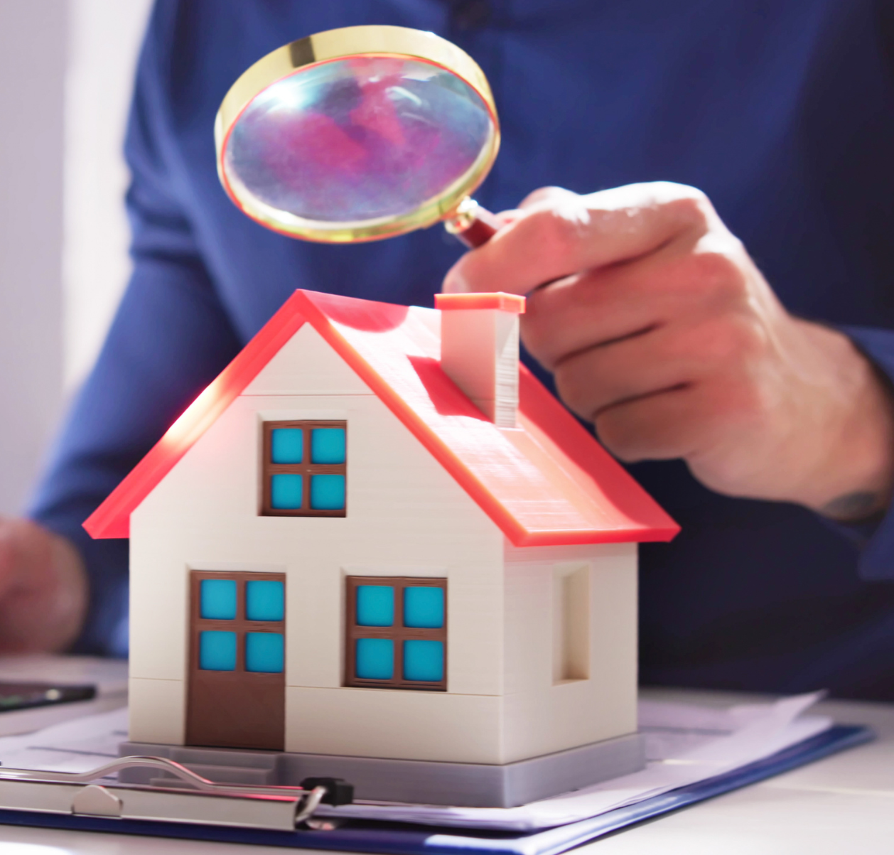 Man holding magnifying glass to model home