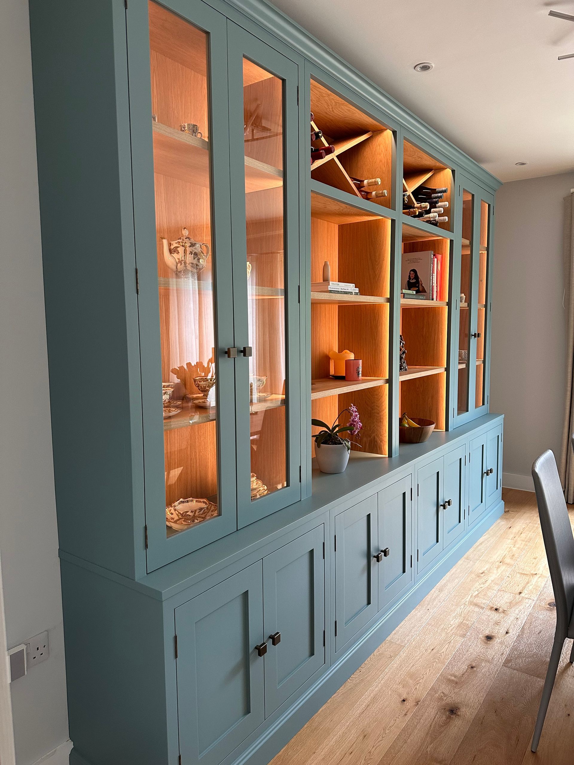 a large blue custom home library with glass doors and shelves in a living room .