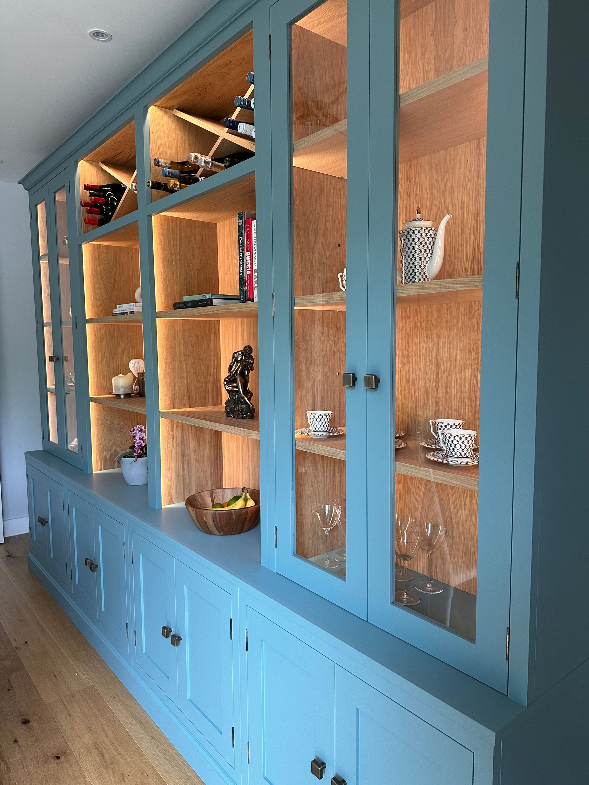 a blue custom home library with glass doors and shelves in a room .