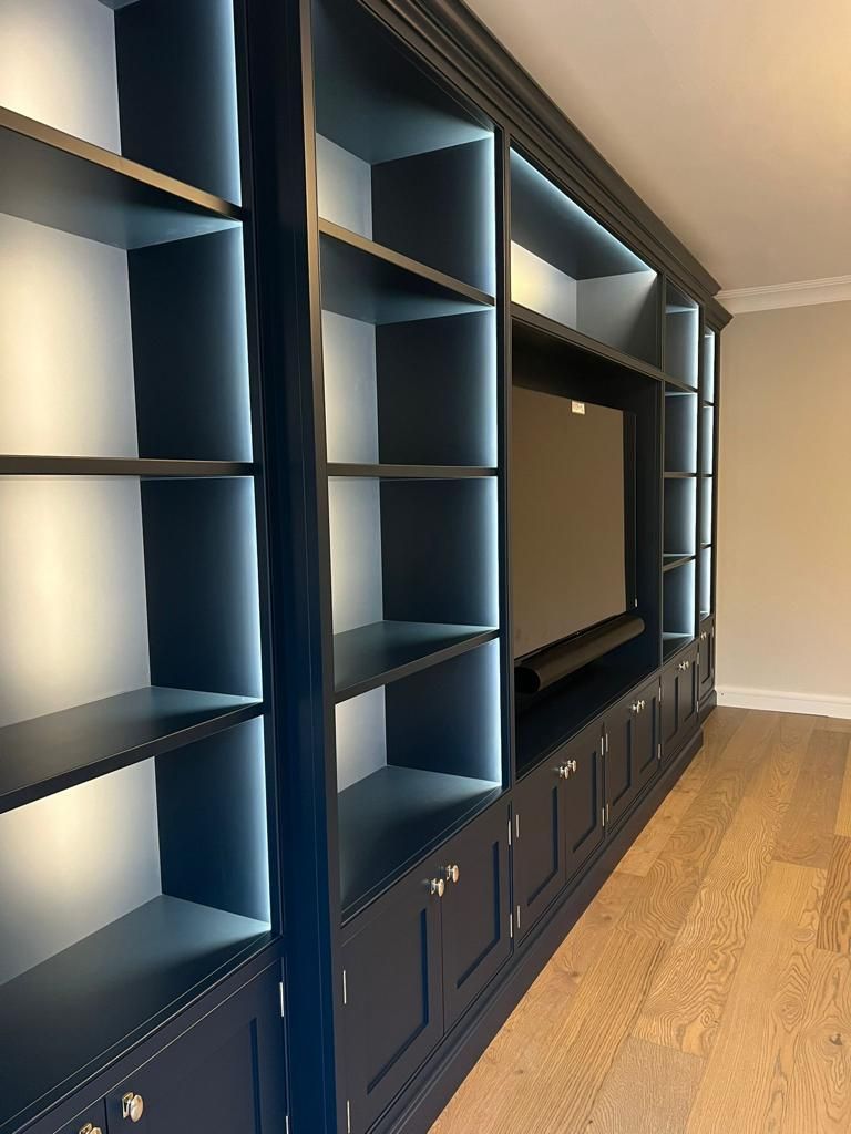 a living room with blue fitted home library and a flat screen tv .