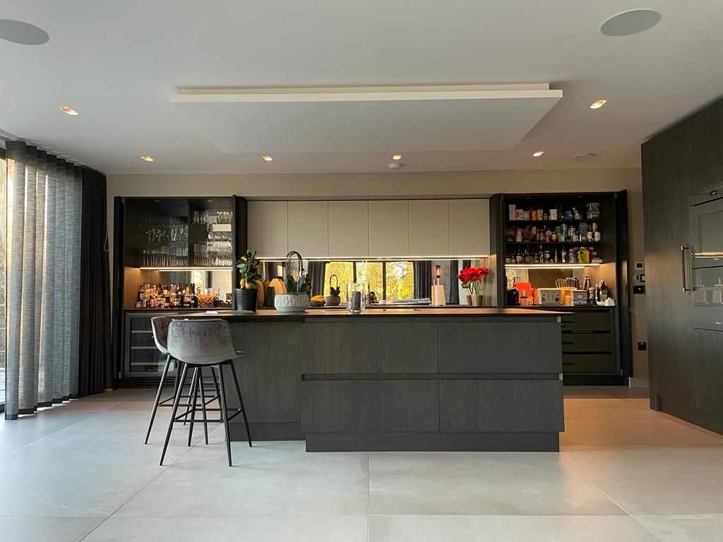 a luxury high end dark gray kitchen with a large island and stools