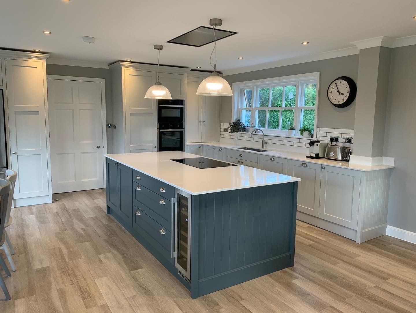 a bespoke kitchen with a large island and a clock on the wall